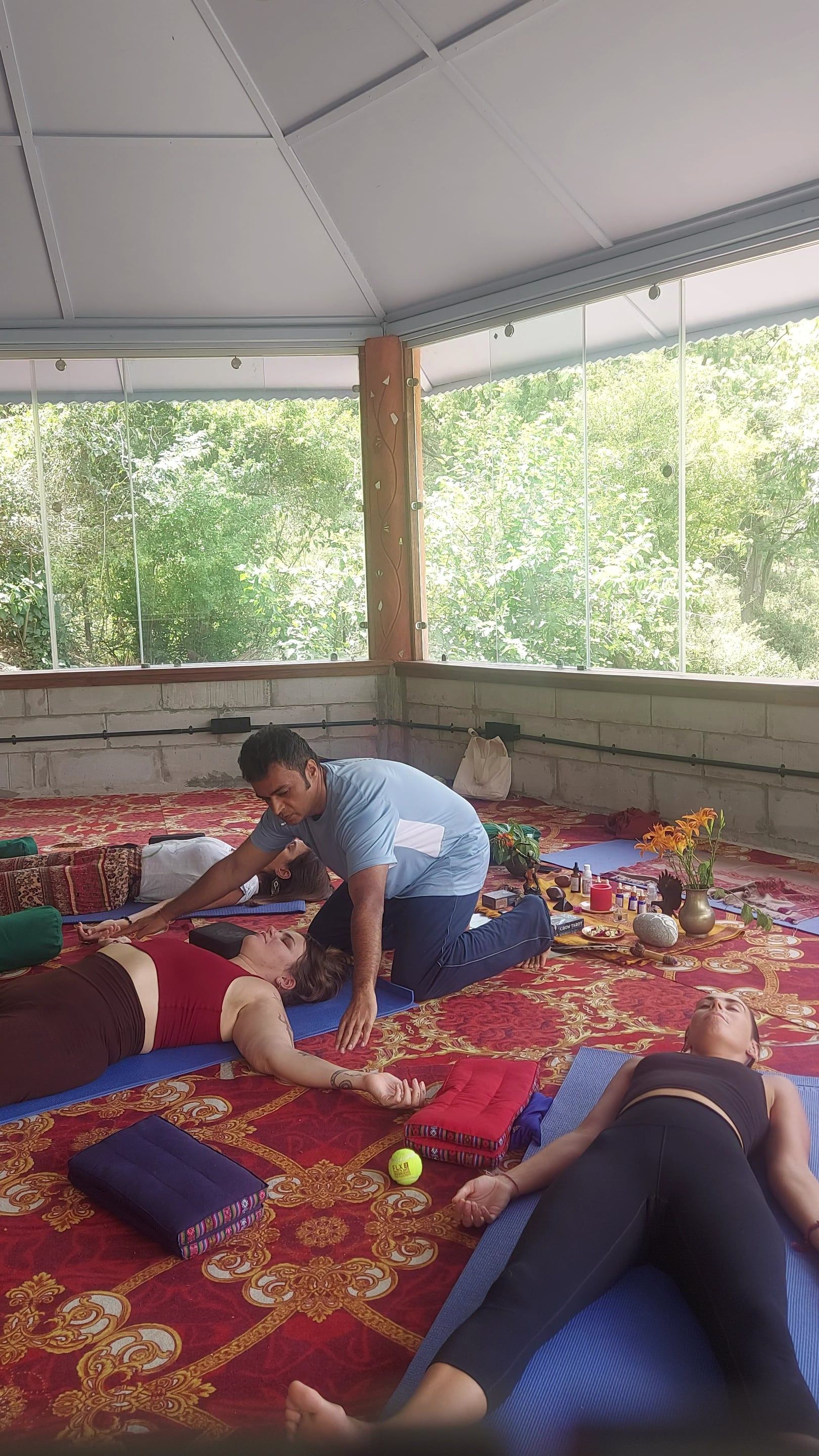 Vishal kneeling beside a participant lying on a mat, offering support during a session