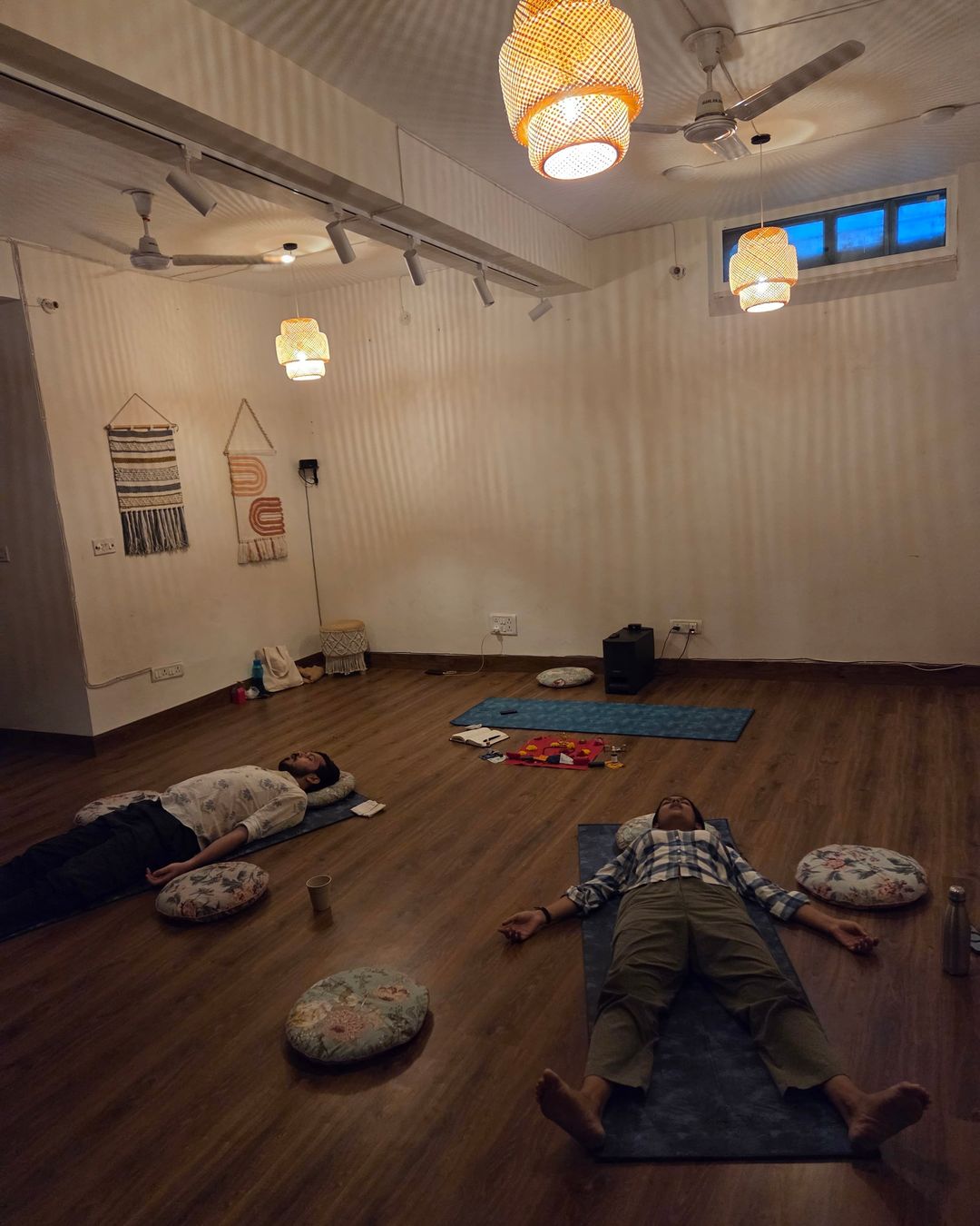 An evening breathwork session: two people lying on mats in a softly lit studio