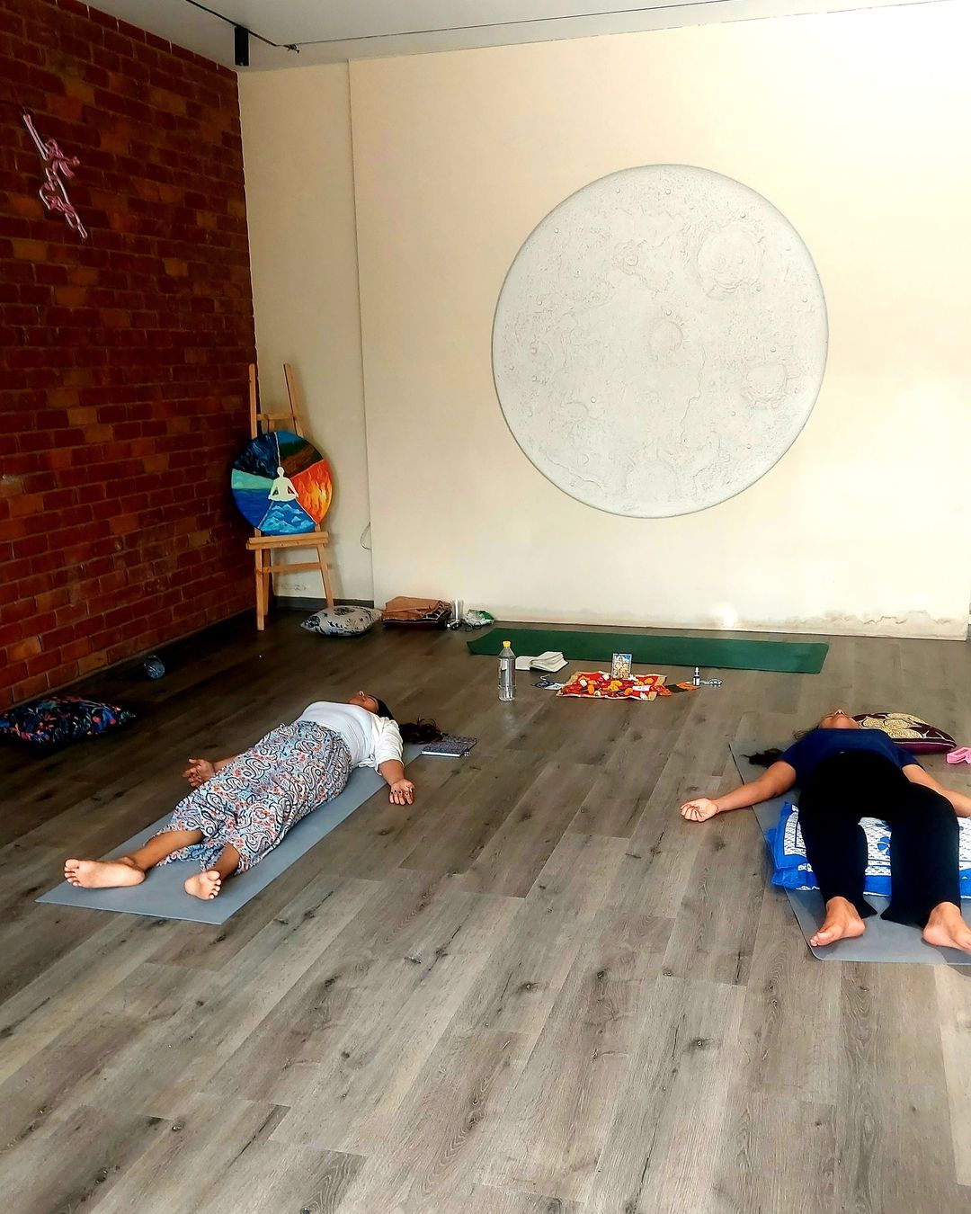 Two people lying on mats in a quiet studio during a breathwork session
